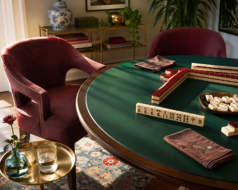 A sunlit game corner styled with mahjong table decor ideas — jade tabletop, burgundy chairs, and tiles mid-play