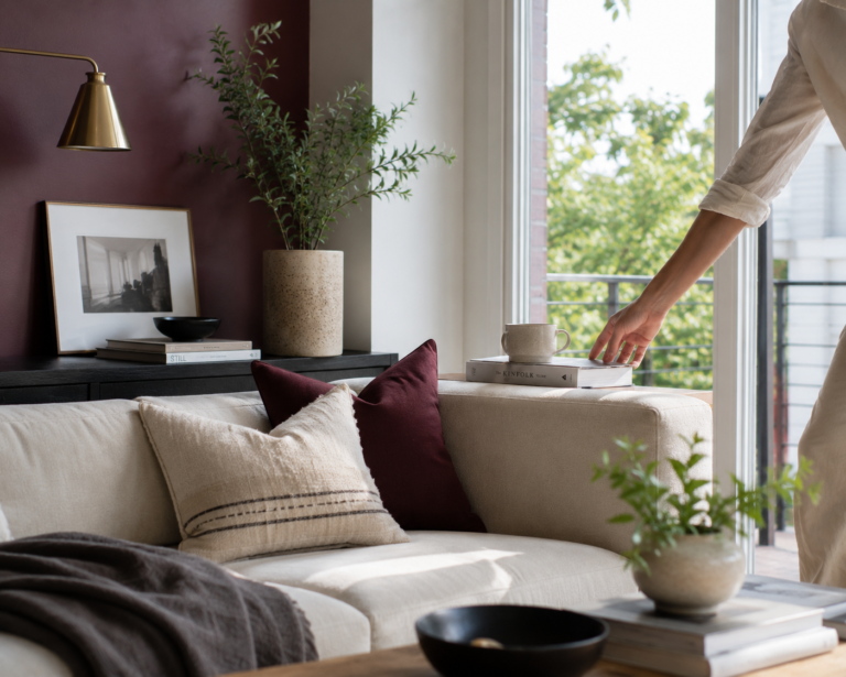Burgundy living room decor styled bright and modern, with a deep red accent wall balanced by natural light and cream textures.