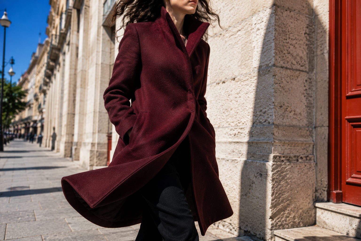Woman walking outdoors in a burgundy funnel neck coat trend 2026 silhouette, wind catching the collar and hem